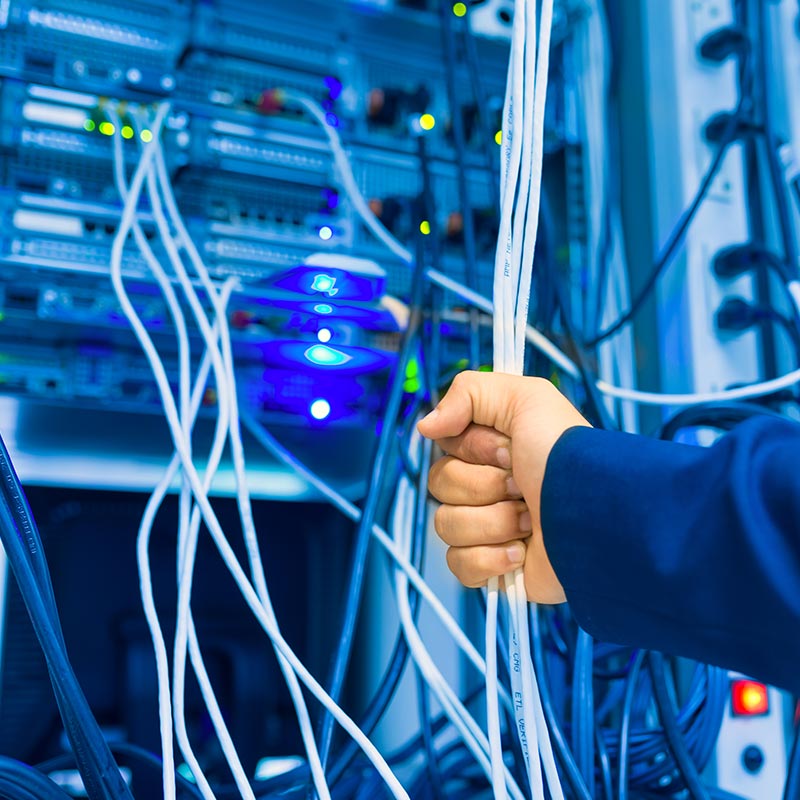 An image of a person holding wires in a server room | Network Support in Falkirk