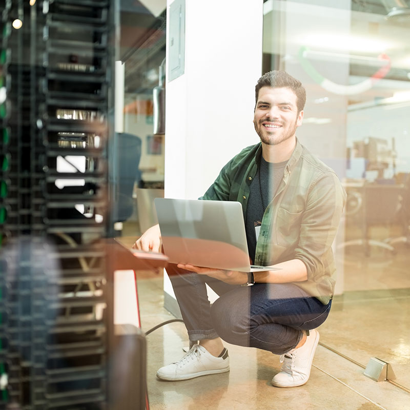 A man holding a laptop in a server room | Network Support in Falkirk