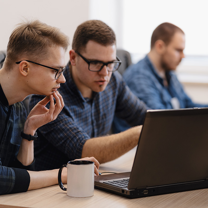 Two people looking at a laptop screen and having a conversation in an office | Cyber Essentials in Falkirk